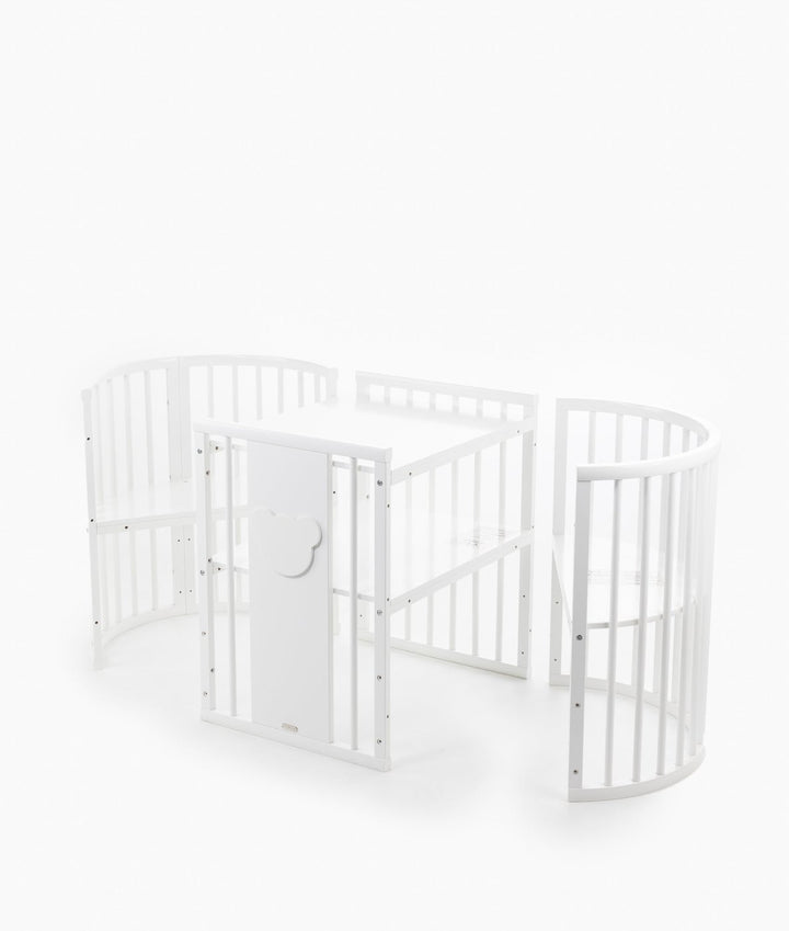 White baby cot with teddy bear design styled in a neutral nursery room