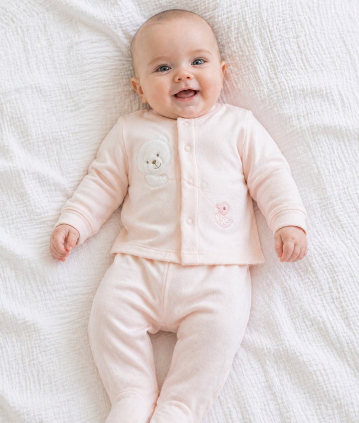 Baby wearing pink two-piece pyjama set with teddy bear and duck embellishments