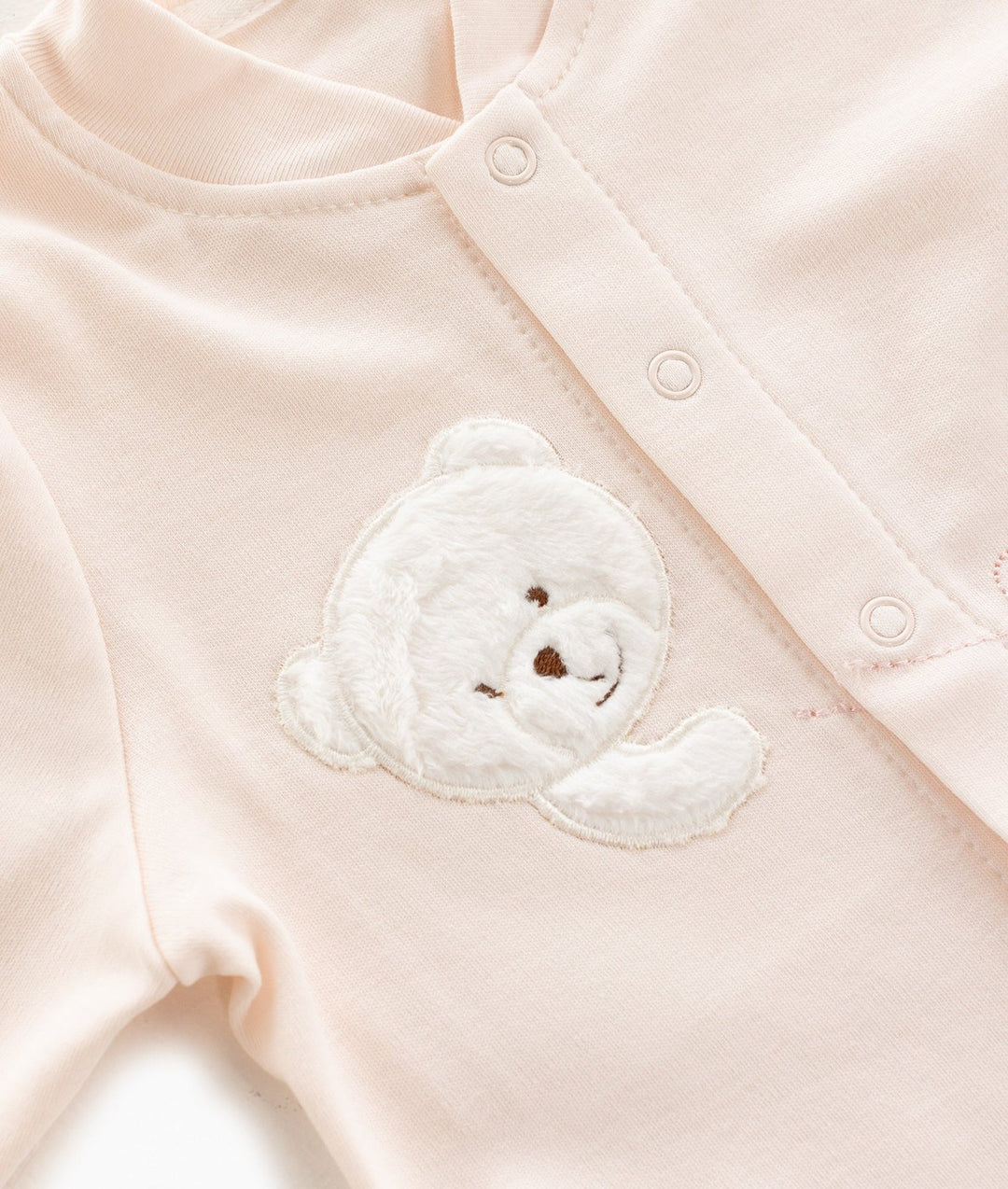 Soft pink cotton baby top with round neckline and textured white fuzzy teddy bear patch