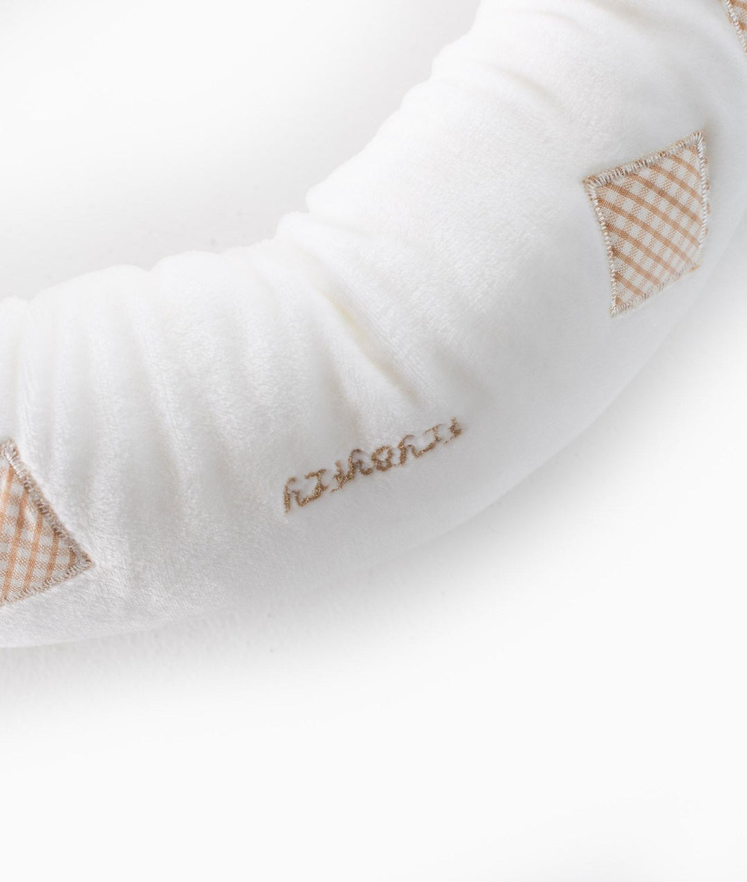 Detail of embroidered text and gingham stitching on white baby bolster