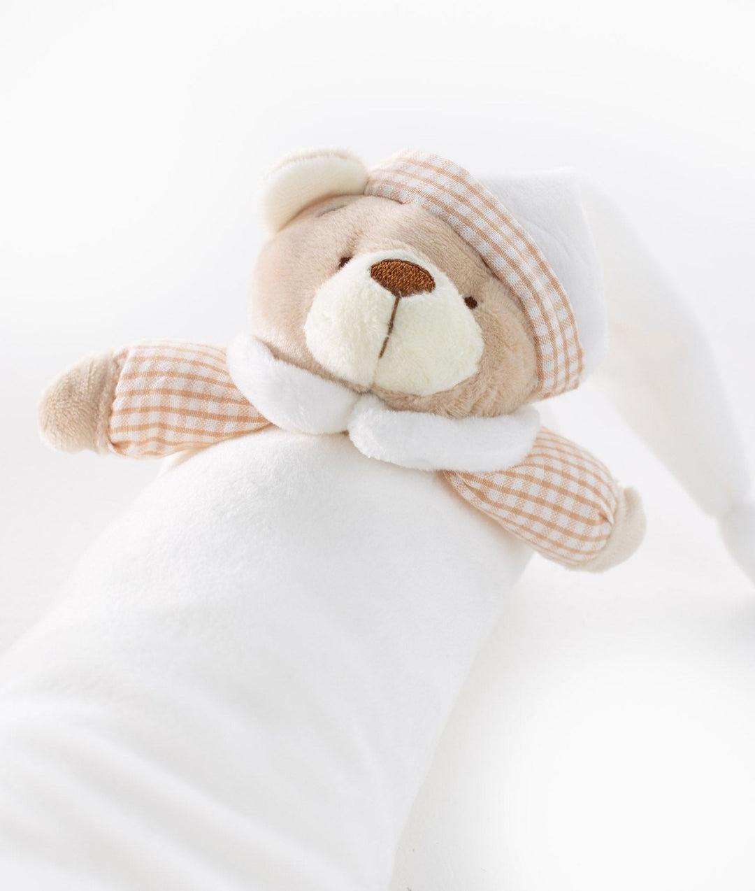 Macro shot of beige plush bear head with checkered band on white bolster