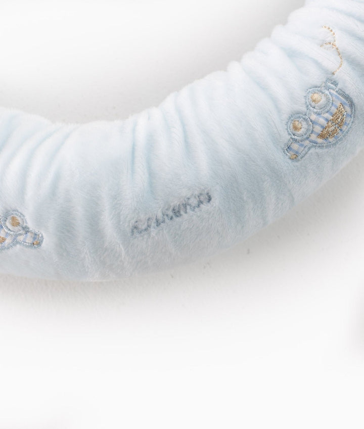 Detail view of grey stitched brand text between owl patches on gathered blue fabric