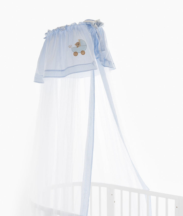 Close-up of light blue gingham trim and teddy bear pram embroidery on the gathered header of a white oval cot canopy