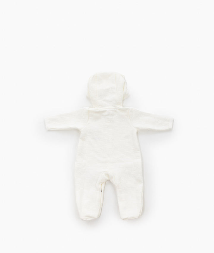 Back view of beige and white hooded bear jumpsuit laid flat showing smooth 100% cotton texture, long sleeves, and rounded hood silhouette