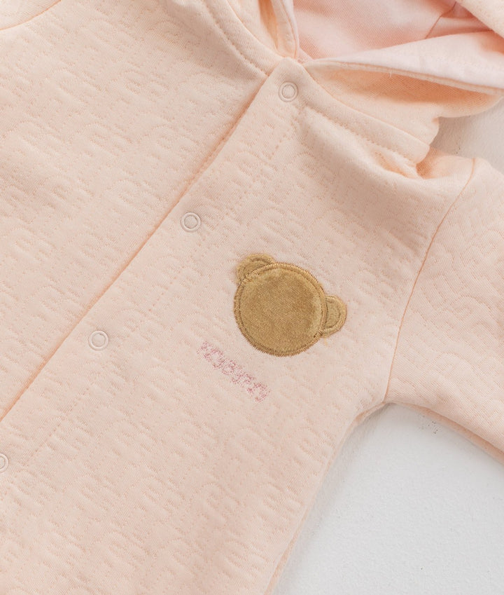 Light pink waffle cotton baby jumpsuit with embroidered bear face patch detail