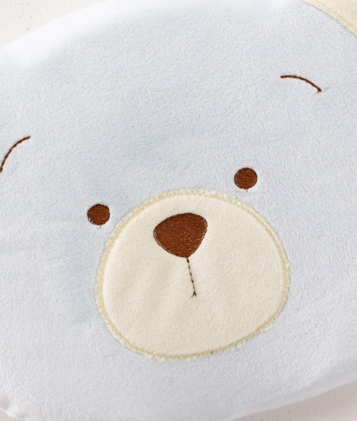 Close-up macro detail of light blue plush fabric texture and embroidered brown nose on baby pillow