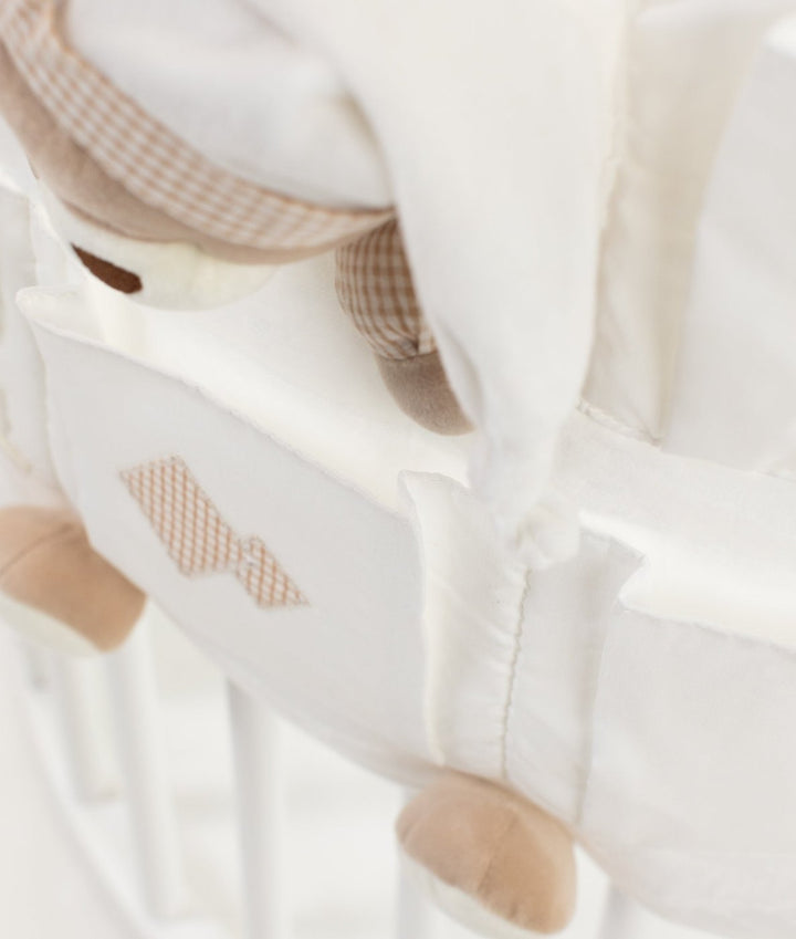 Beige gingham diamond patch detail on white fabric nursery organiser pocket with plush bear attached to crib rail