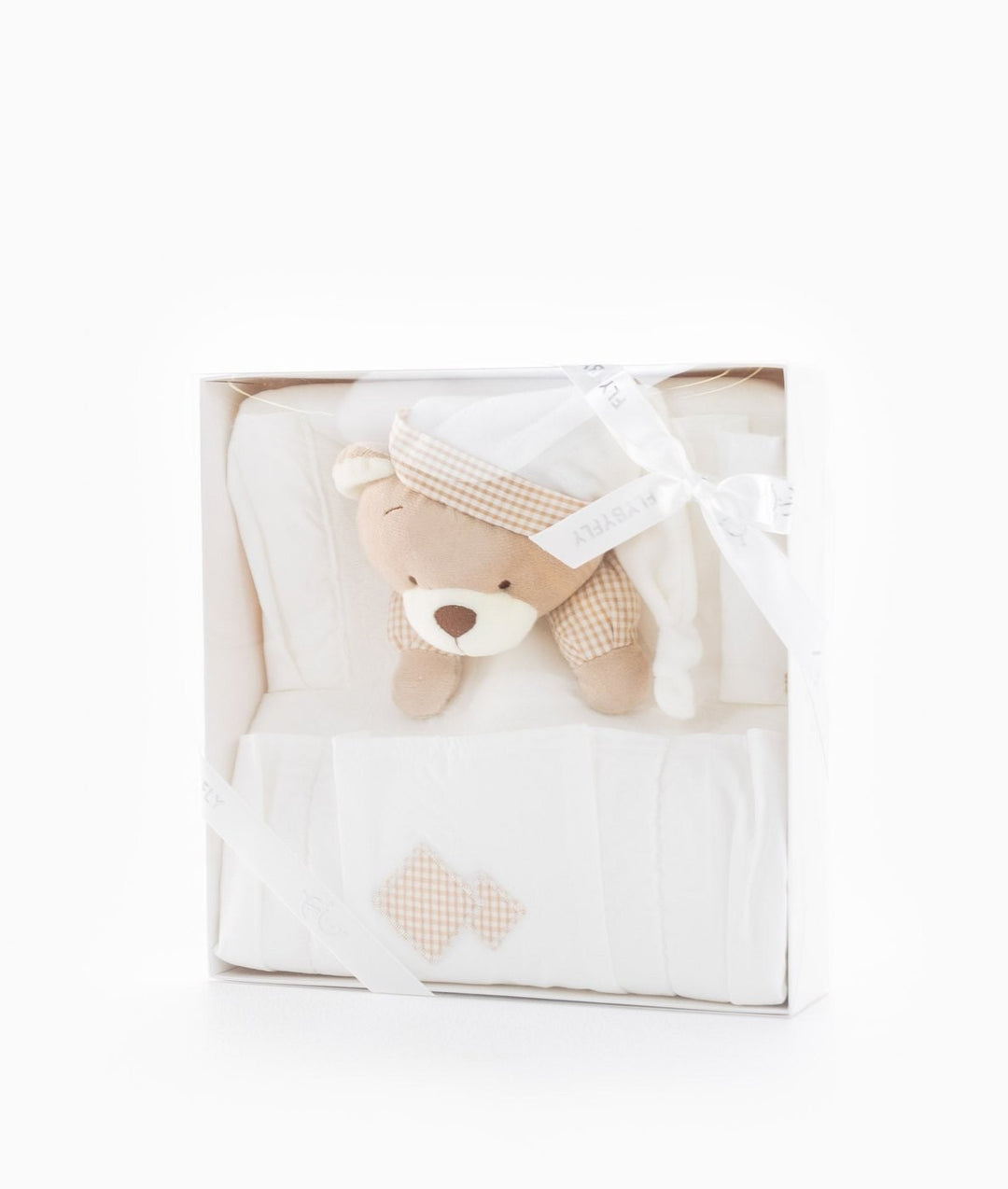 White gift box containing folded cream nursery organiser with beige gingham accents and teddy bear wearing checkered hat