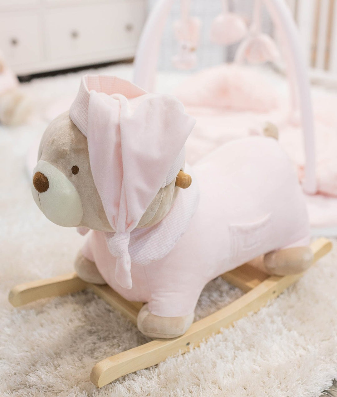 Pink plush bear rocking horse with natural wooden runners and tied hood