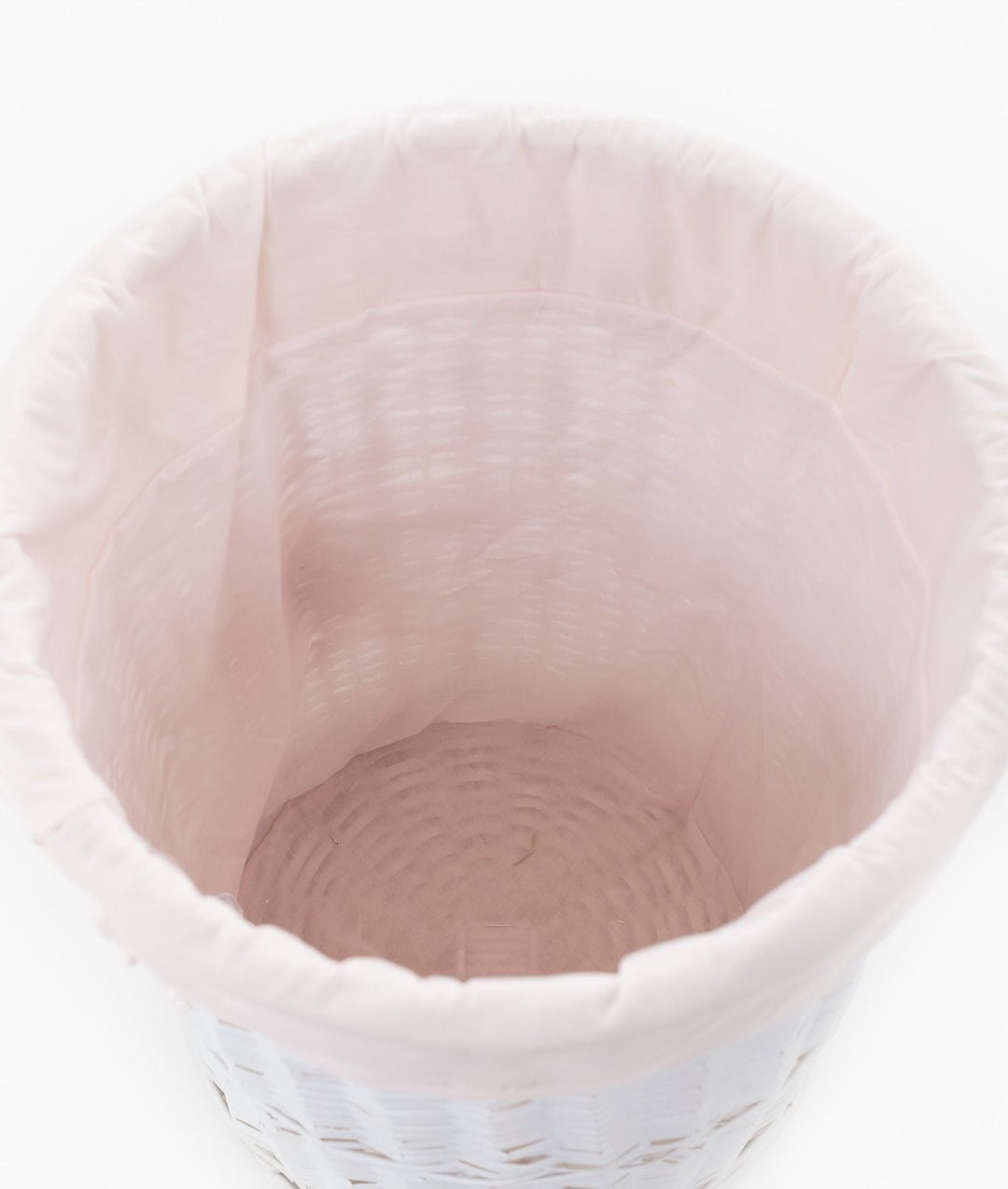 Top-down view of white wicker basket with draped pink fabric liner
