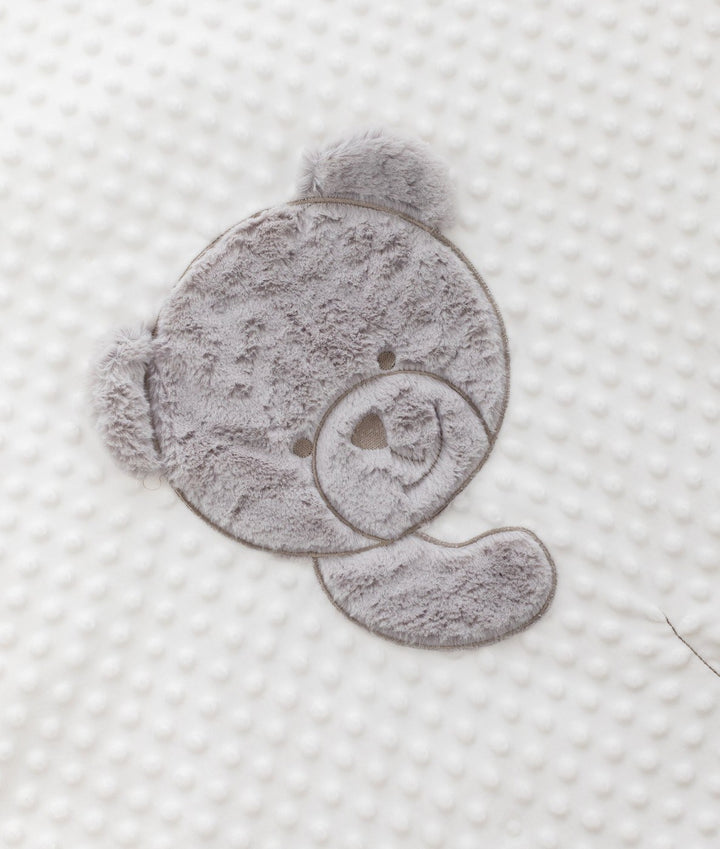 Plush grey teddy bear face patch on dimpled white bubble fabric