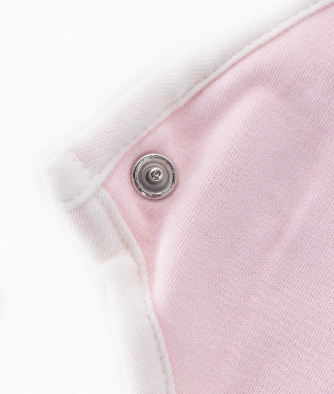 Silver snap fastener detail on pink baby bib with white ribbed neck binding