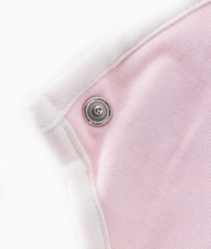 Silver snap fastener detail on pink baby bib with white ribbed neck binding
