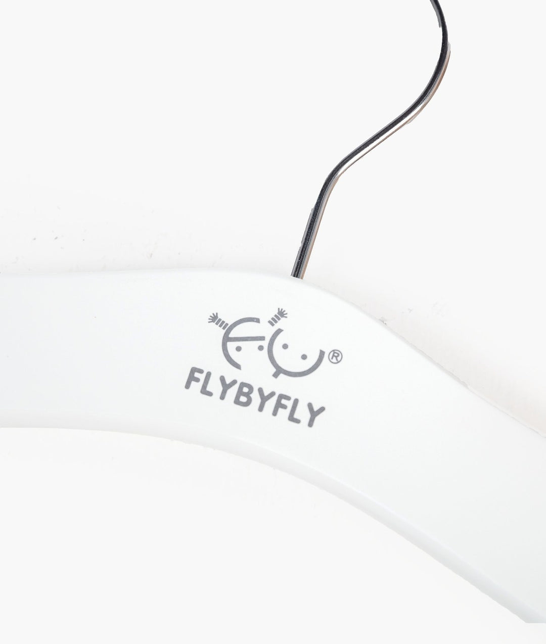 Close-up of white wooden baby hanger surface with grey FLYBYFLY logo print